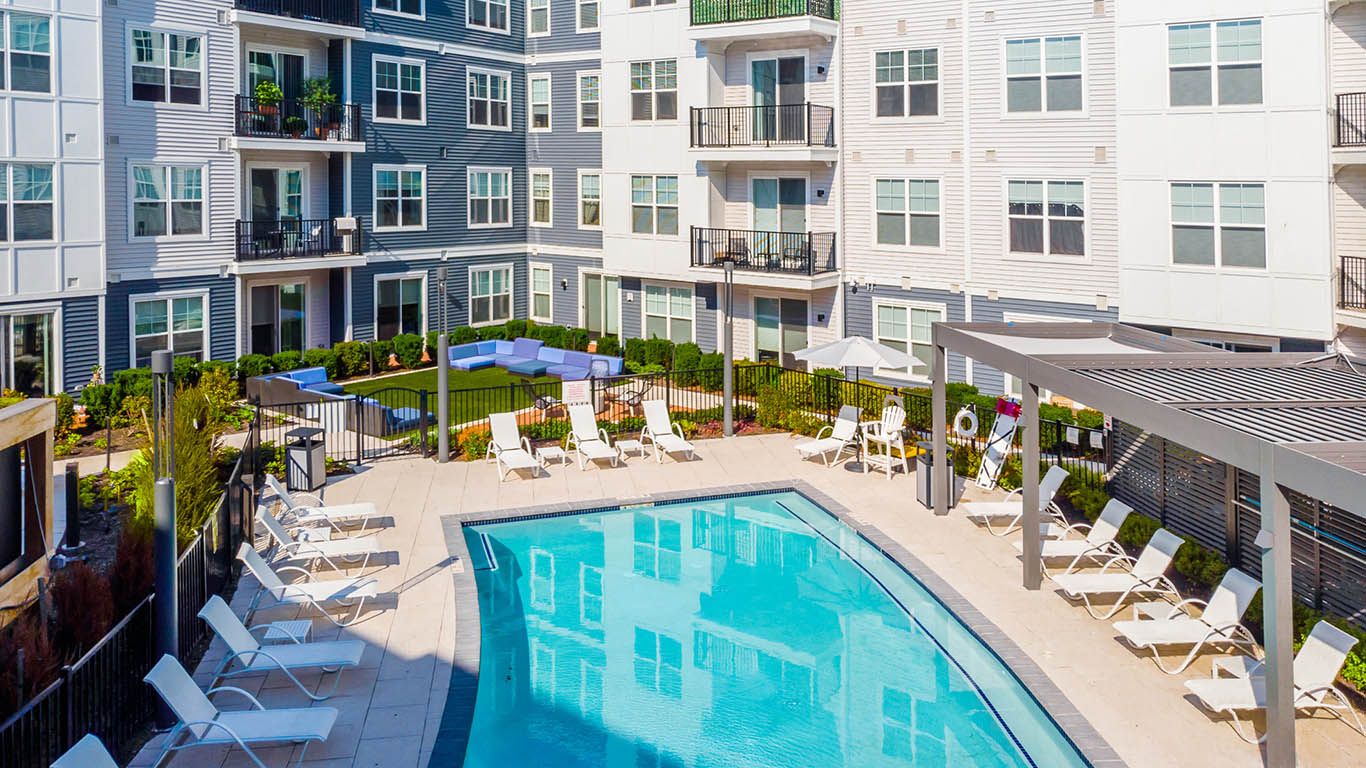 View of pool, grass, and apartments