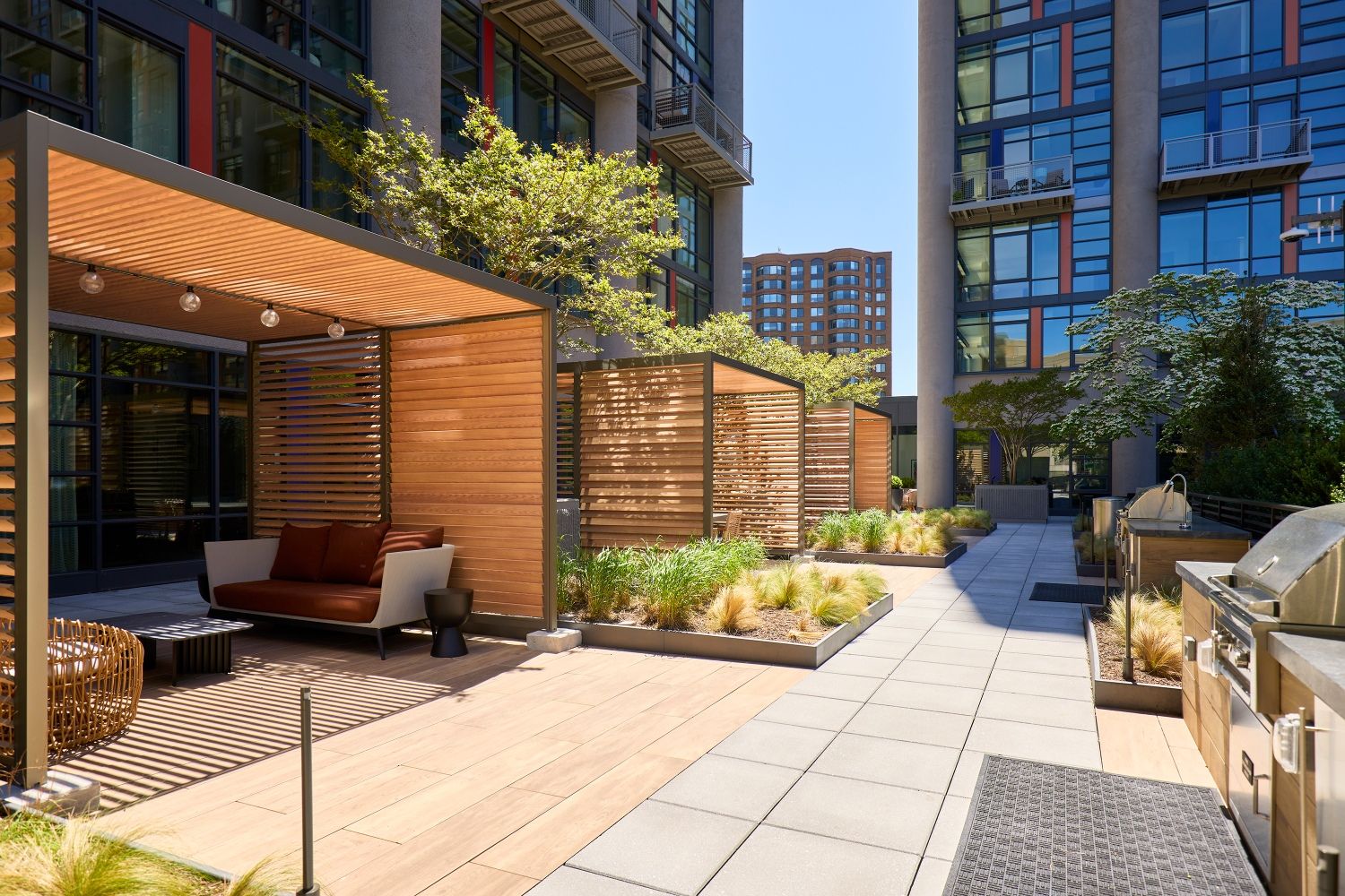 Private cabana lounges adjacent to grilling stations and lush landscaping