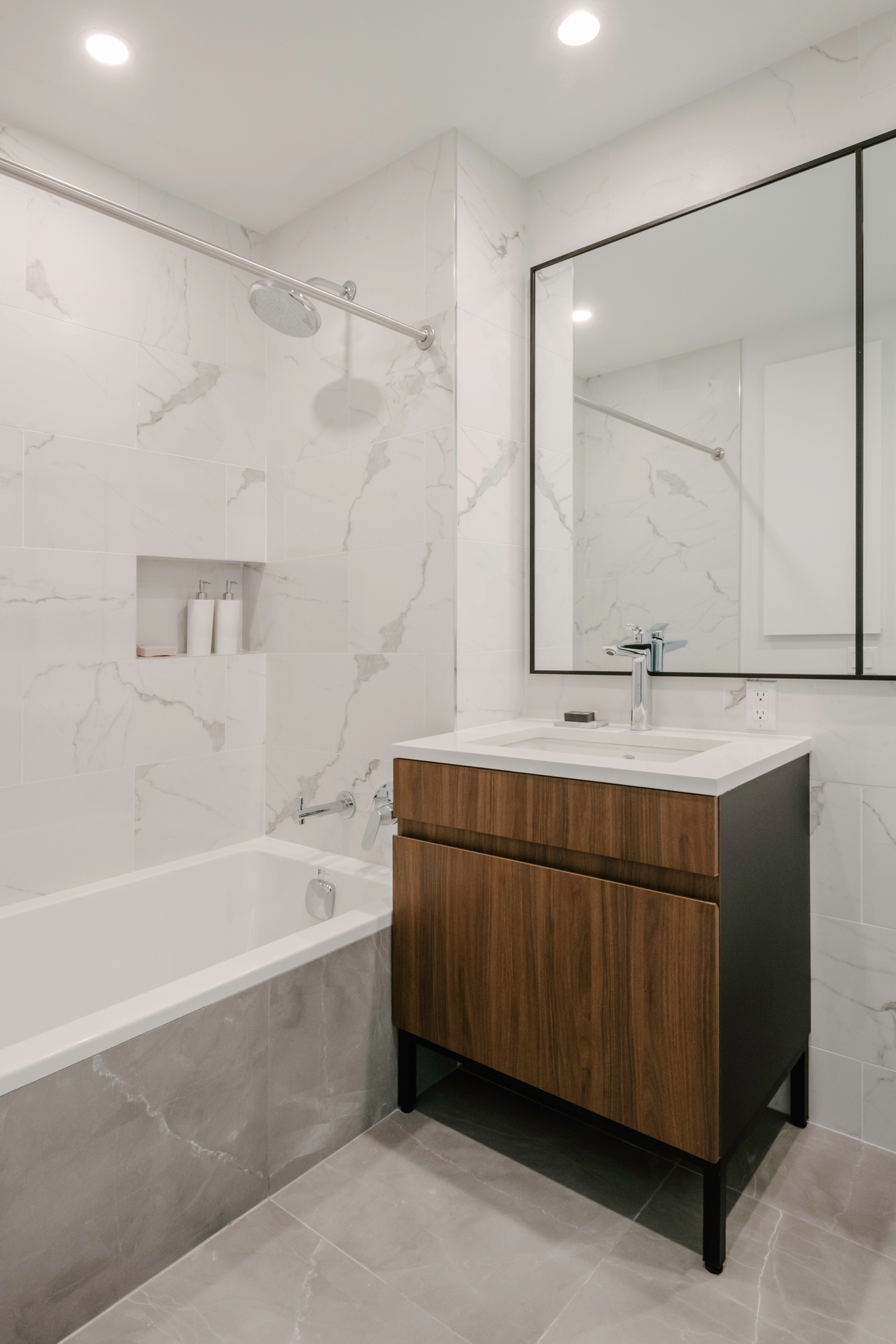 Modern bathroom with a bathtub, wooden vanity, and a large mirror.