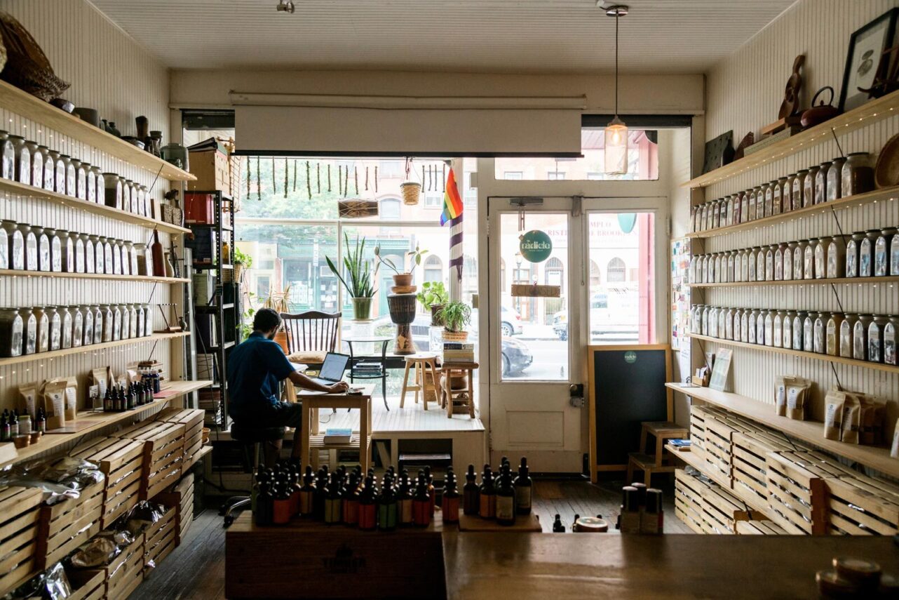 Cozy shop interior with shelves of jars and a person working at a table.