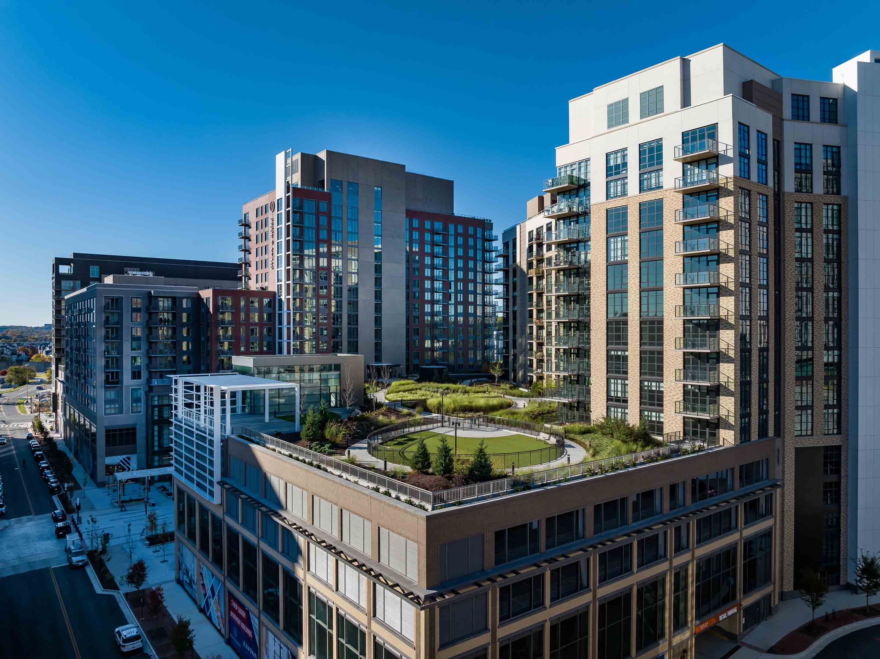 Modern urban buildings with rooftop greenery under a clear blue sky.