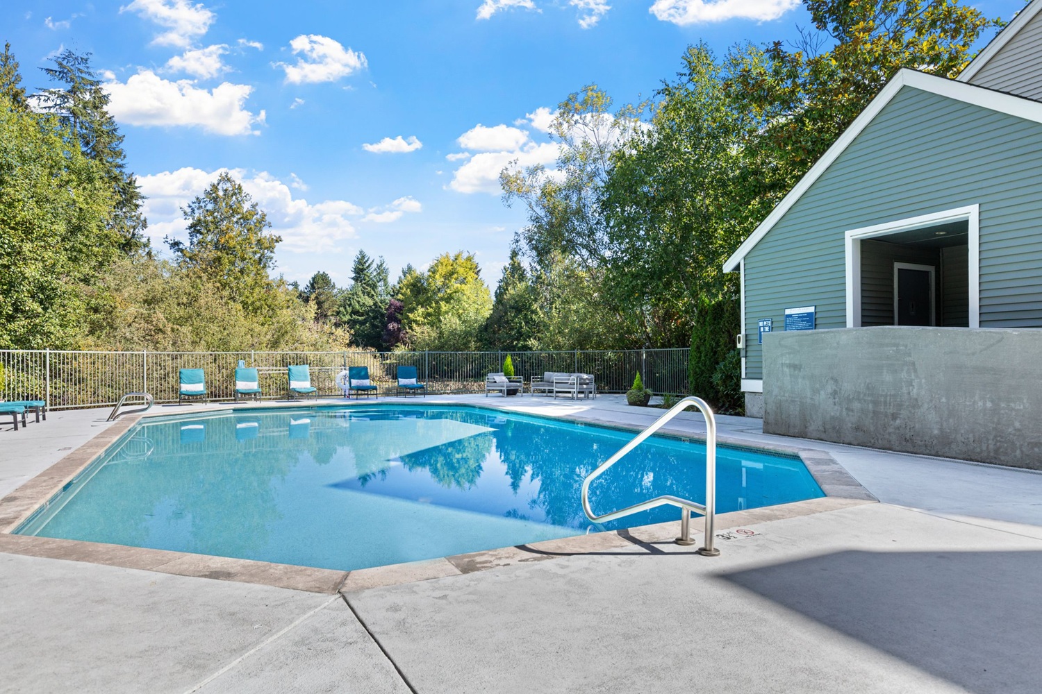 Outdoor swimming pool with lounge seating and mature trees at On the Green at Harbour Pointe.