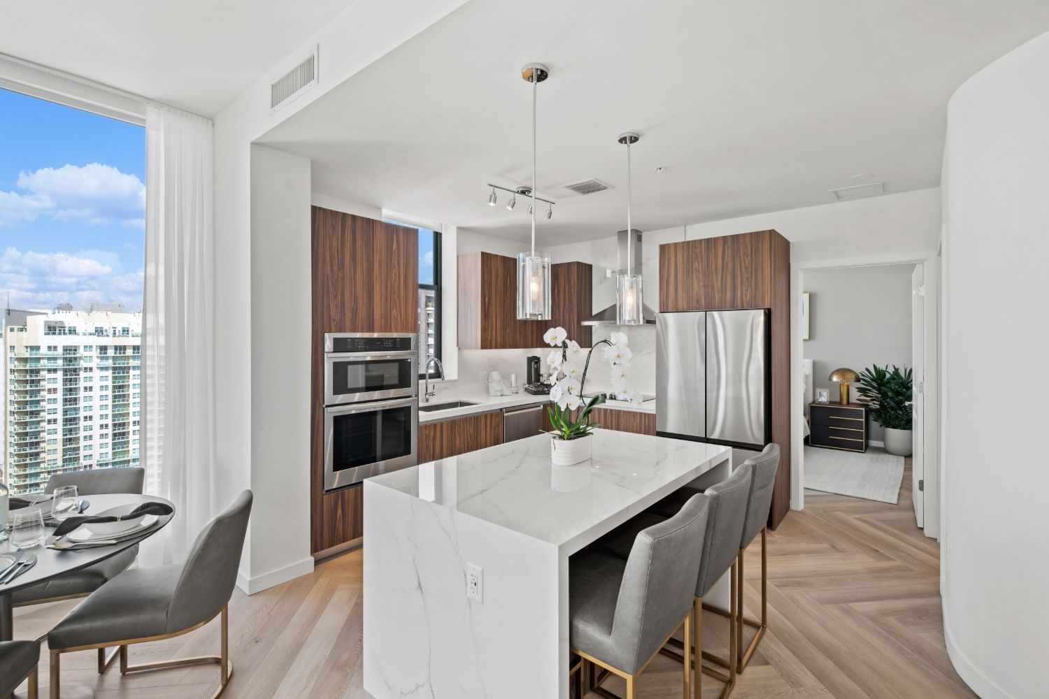 Modern kitchen with wooden cabinets, stainless steel appliances, and a minimalist dining area.