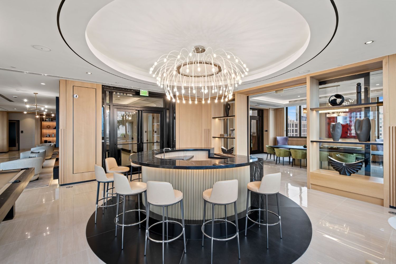Modern lounge with a circular bar, elegant chandelier, and stylish seating.