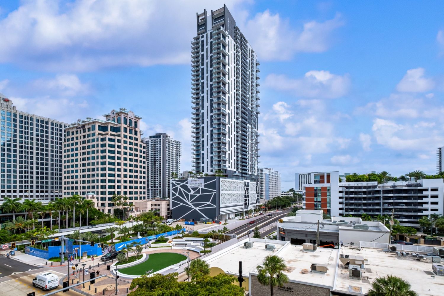 City skyline featuring a modern skyscraper and green park with blue sky.