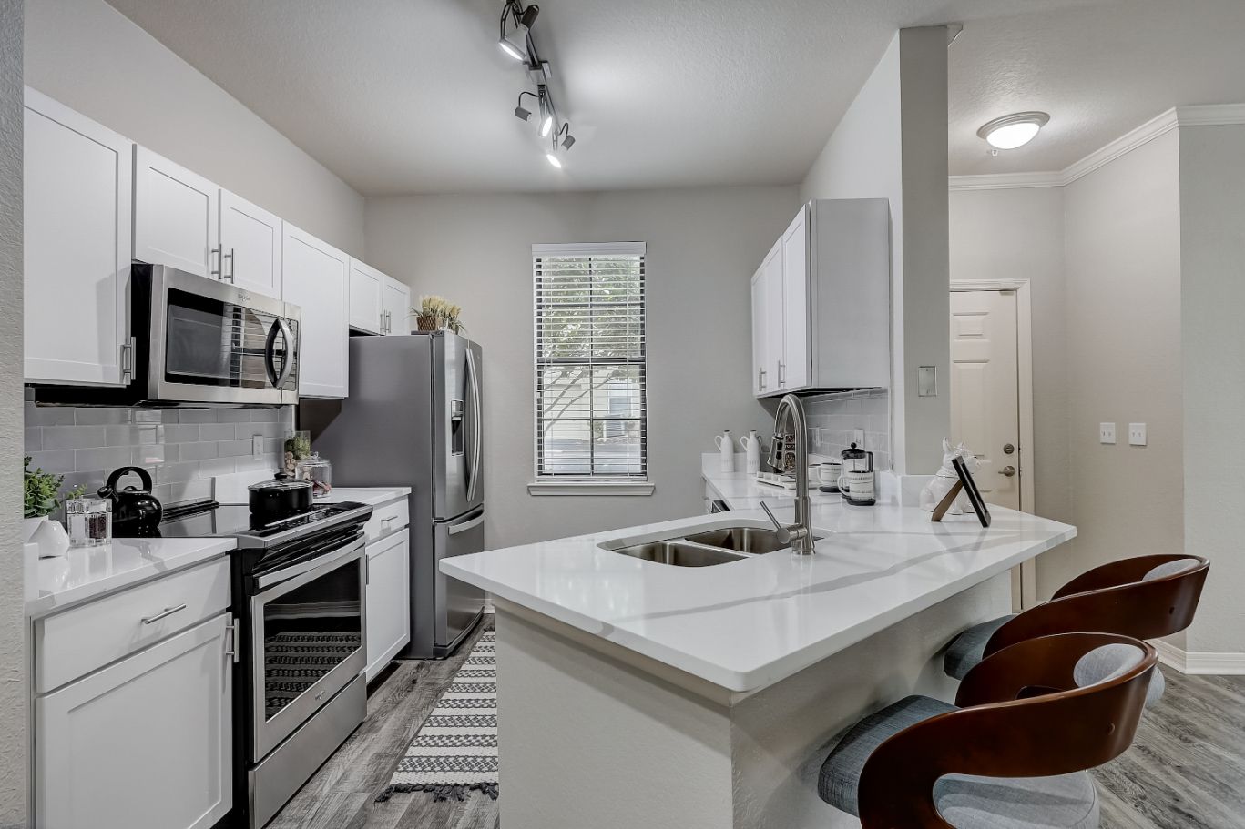 Modern kitchen with stainless steel appliances and a small island with two bar stools.