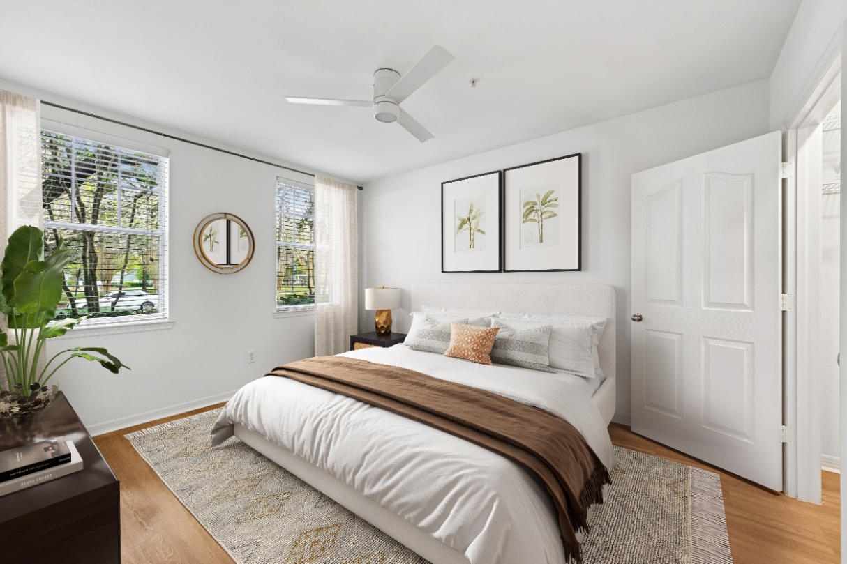 Modern bedroom with a bed, artwork, large windows, and neutral decor.