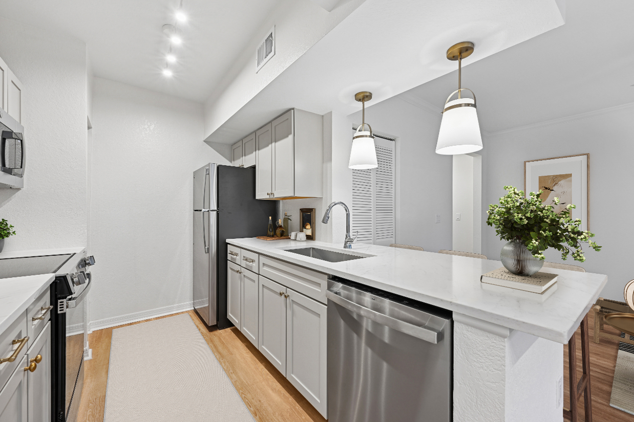 Modern kitchen with white cabinets, stainless appliances, and pendant lighting.