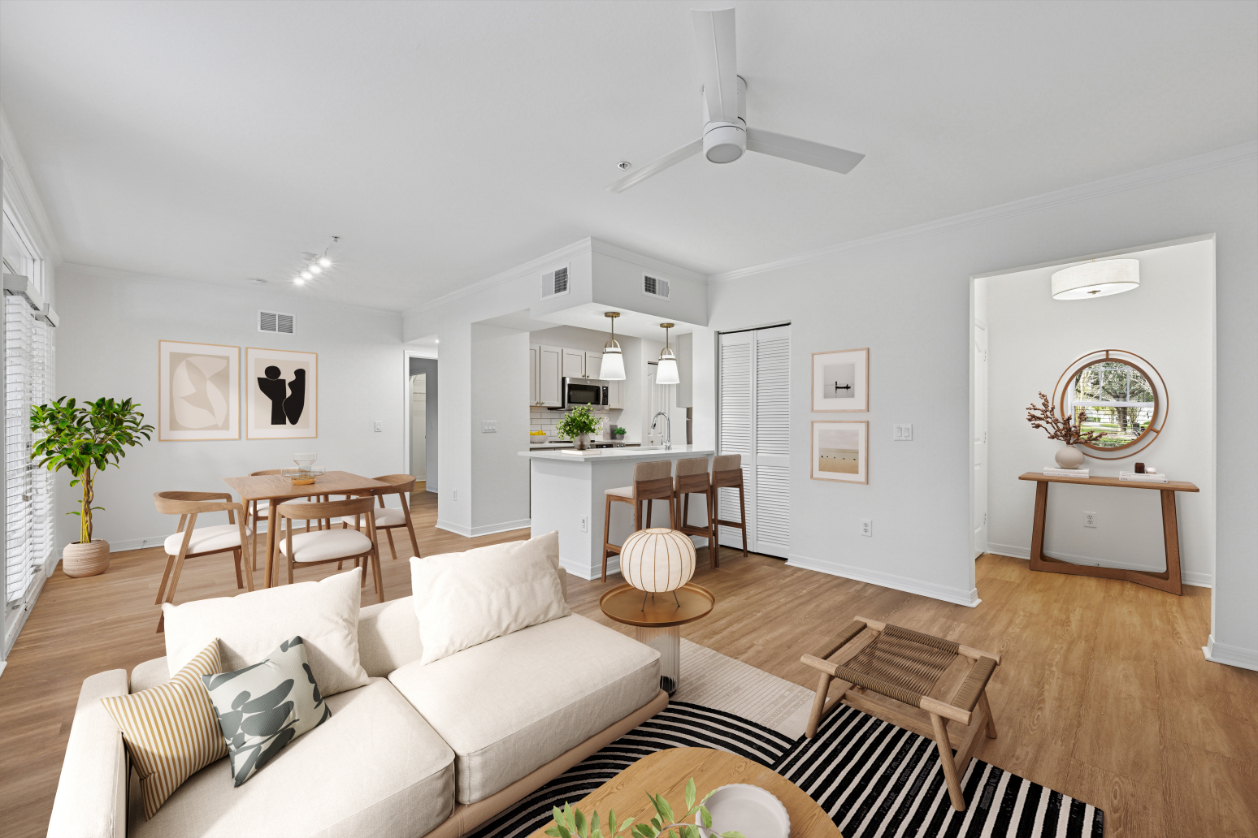 Bright, modern living room with a sofa, wood accents, and open kitchen view.