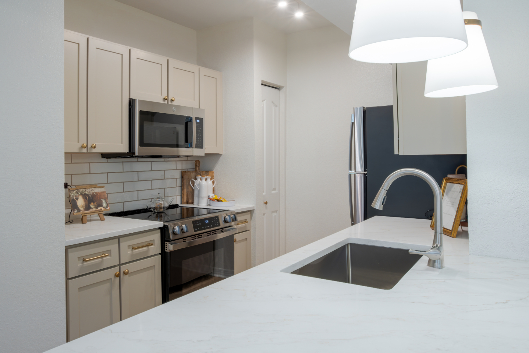Modern kitchen with stainless steel appliances and marble countertops.