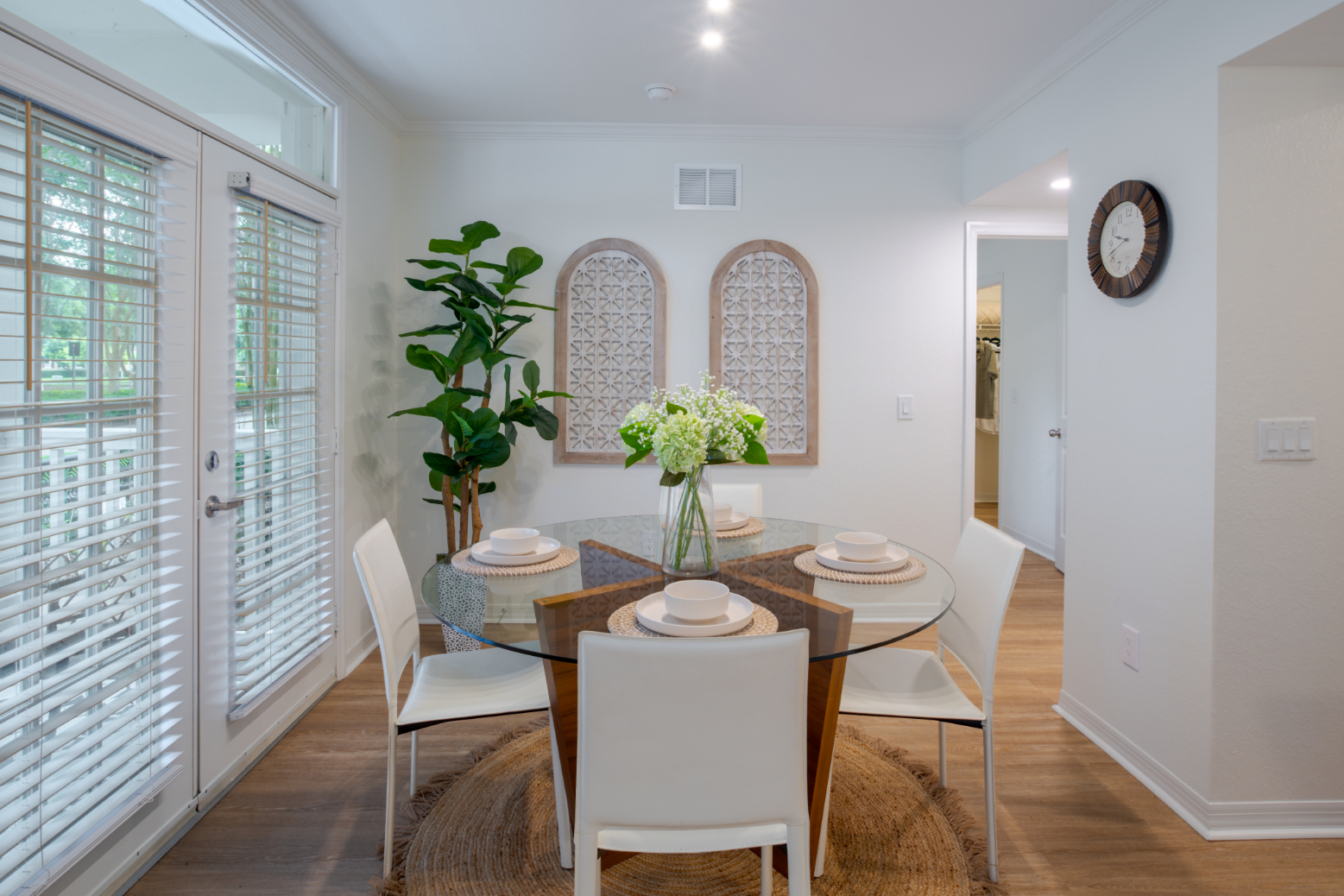 Bright dining area with a round table, chairs, and greenery.
