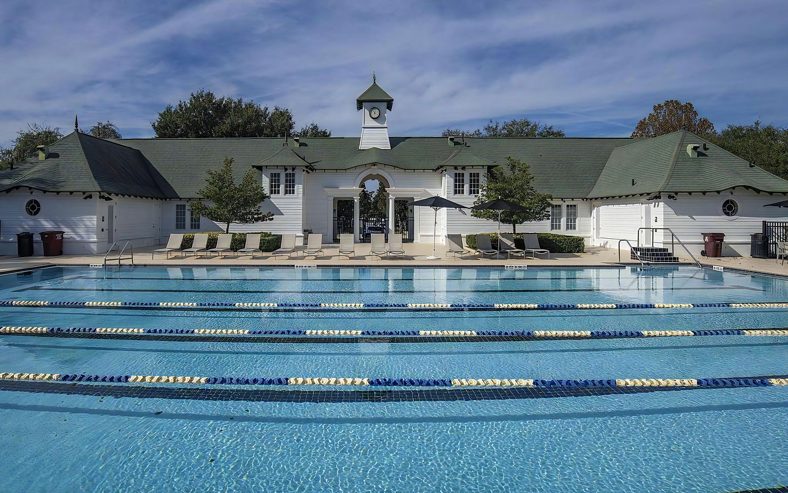 Building with green roofs and a pool in front under a blue sky.