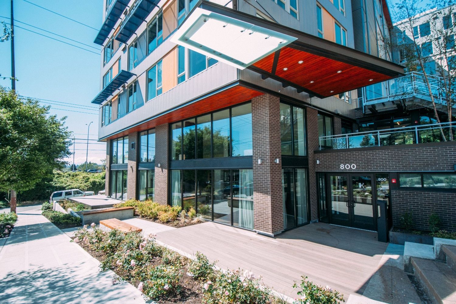 Modern building entrance with glass doors and landscaped walkway.