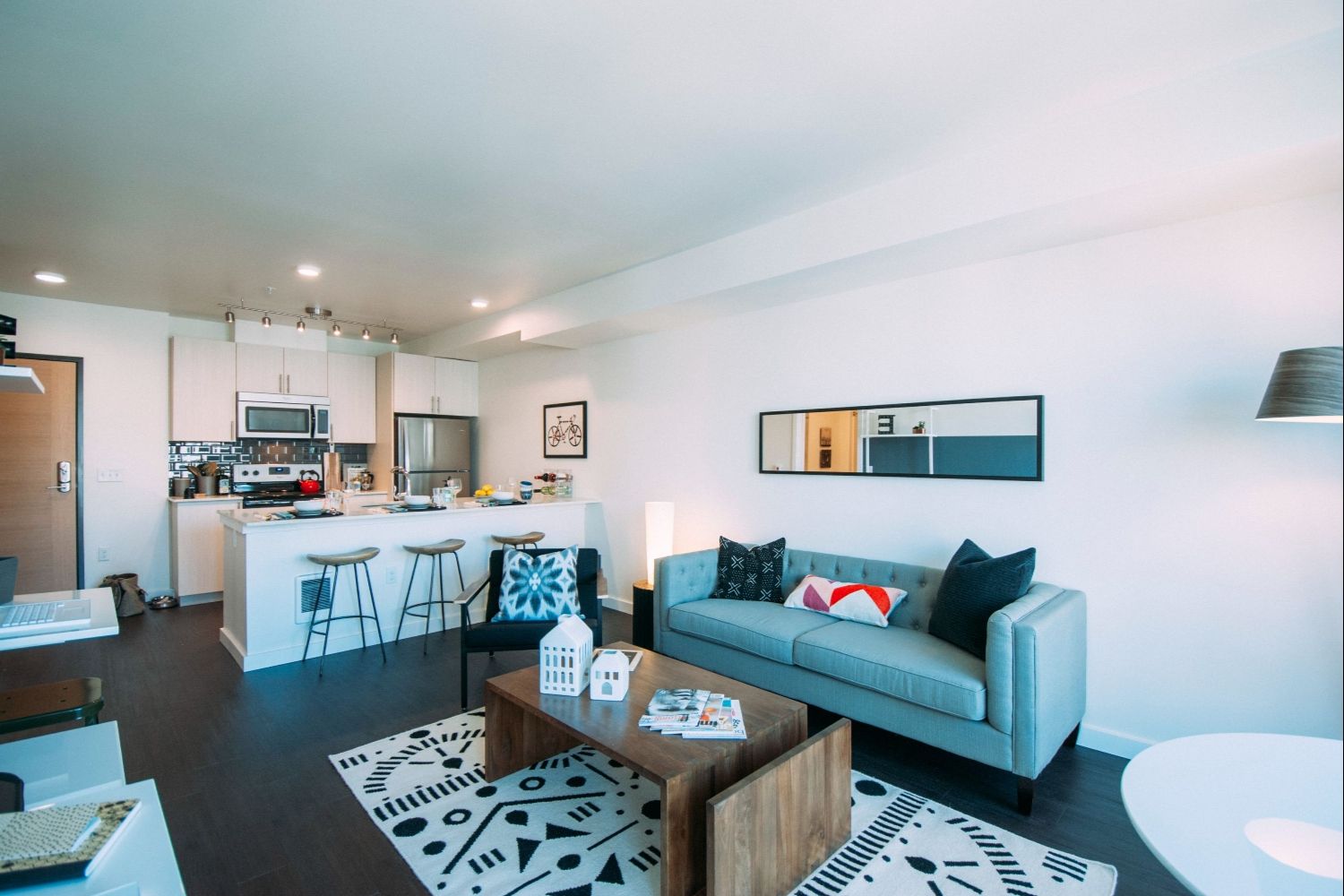 Modern living room with a sofa, coffee table, and open kitchen in a bright space.