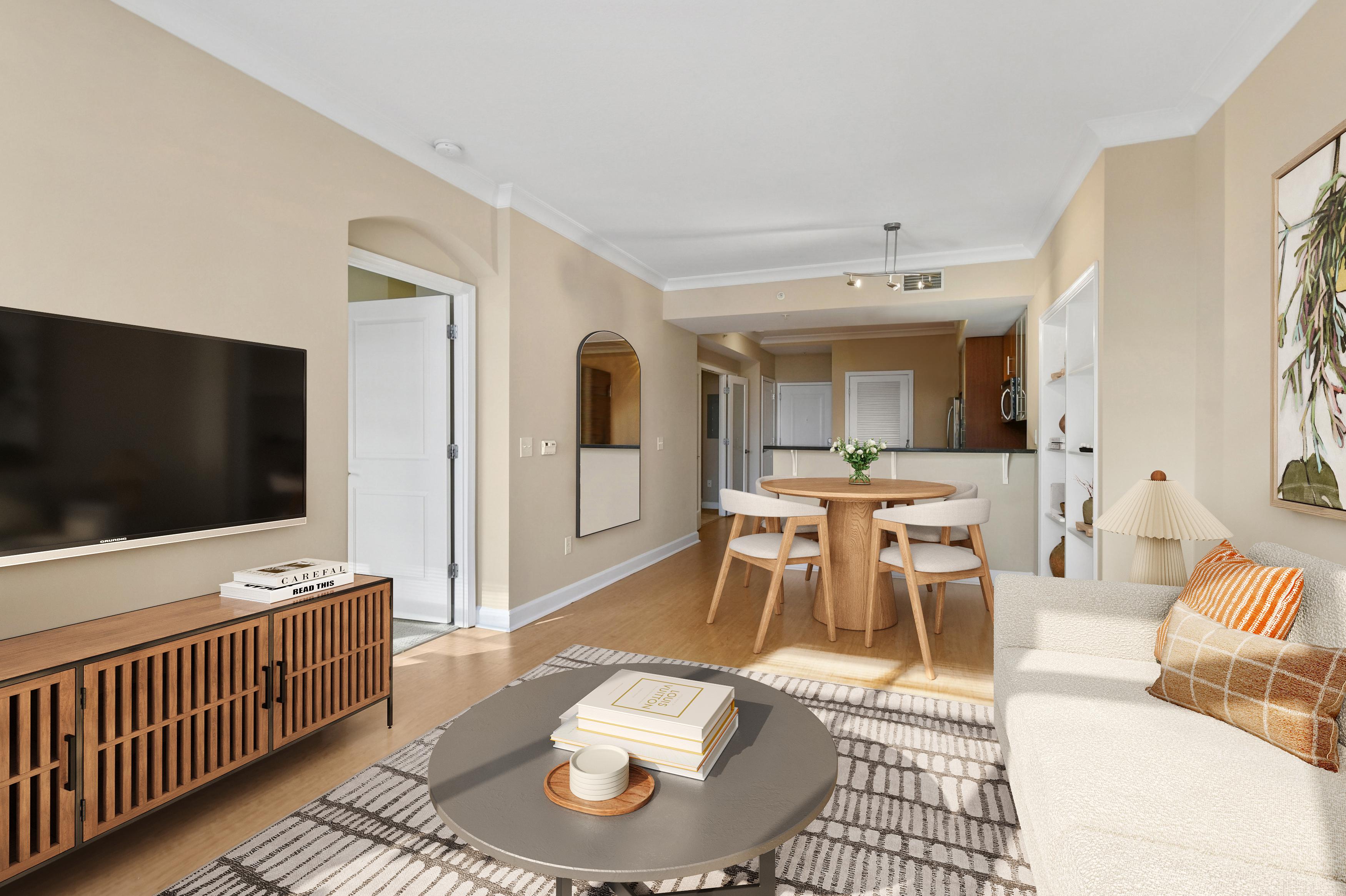 Modern living room with a TV, dining table, and light-colored furniture.