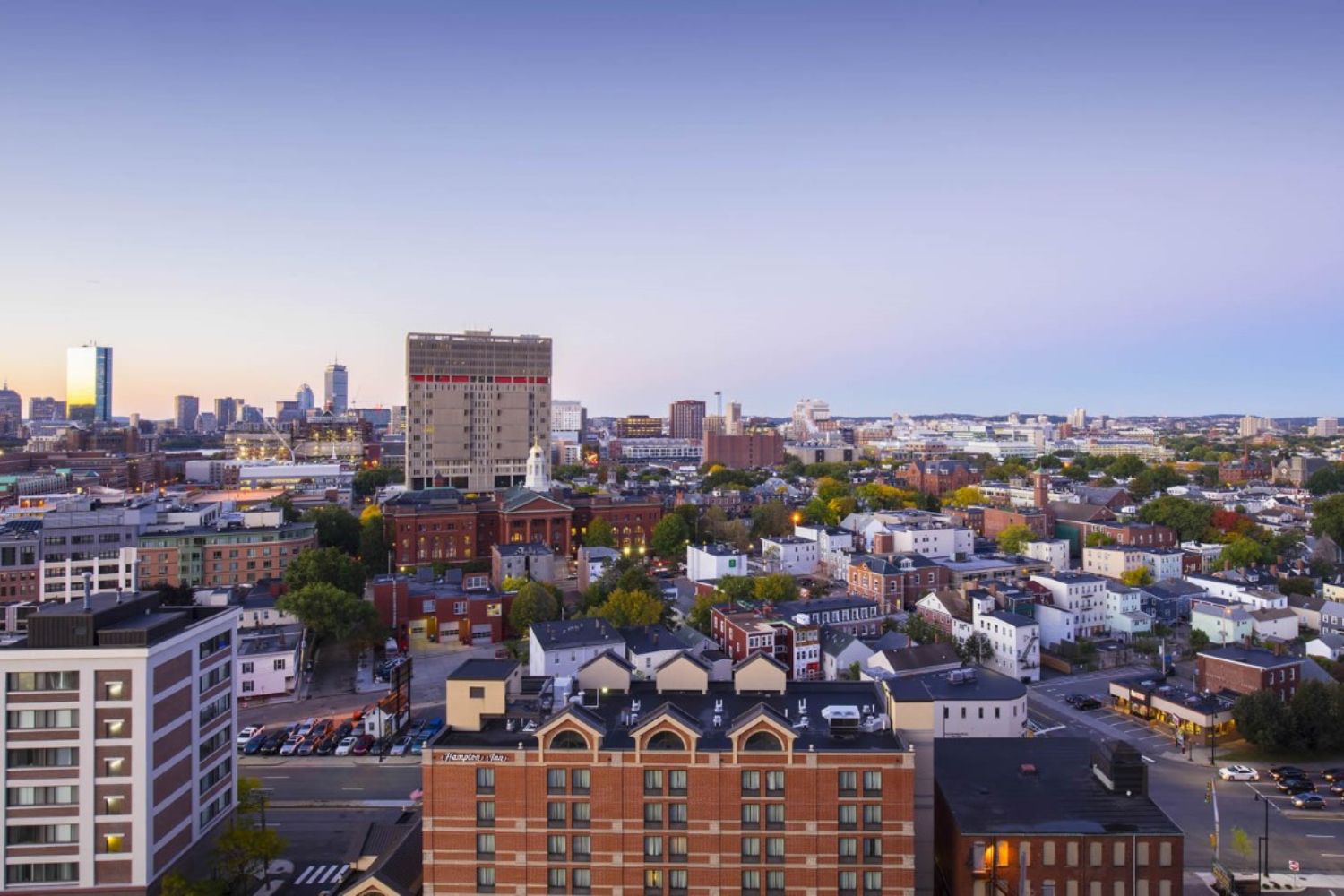 A panoramic view of a city's skyline at dusk with buildings and a clear sky.