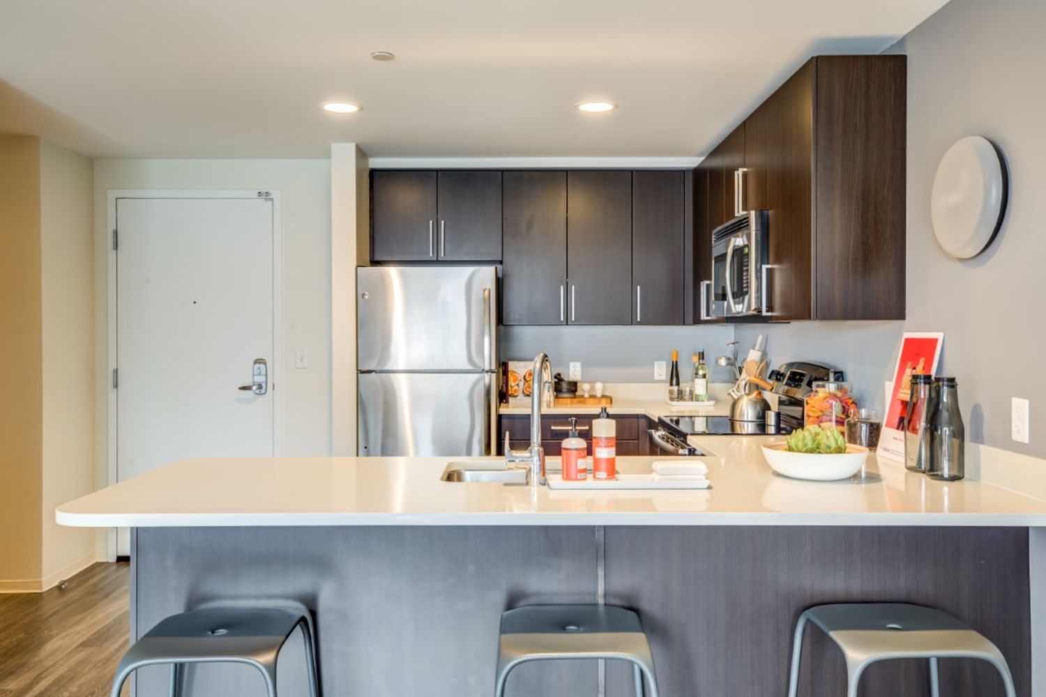 Modern kitchen with dark cabinetry, stainless steel appliances, and a bar counter.