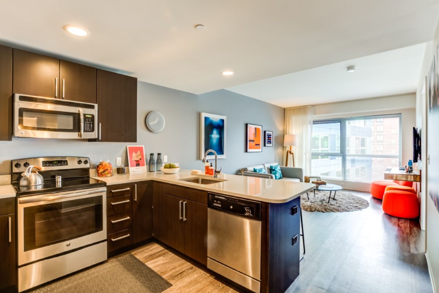Modern kitchen with stainless steel appliances and a cozy living area in a bright apartment.