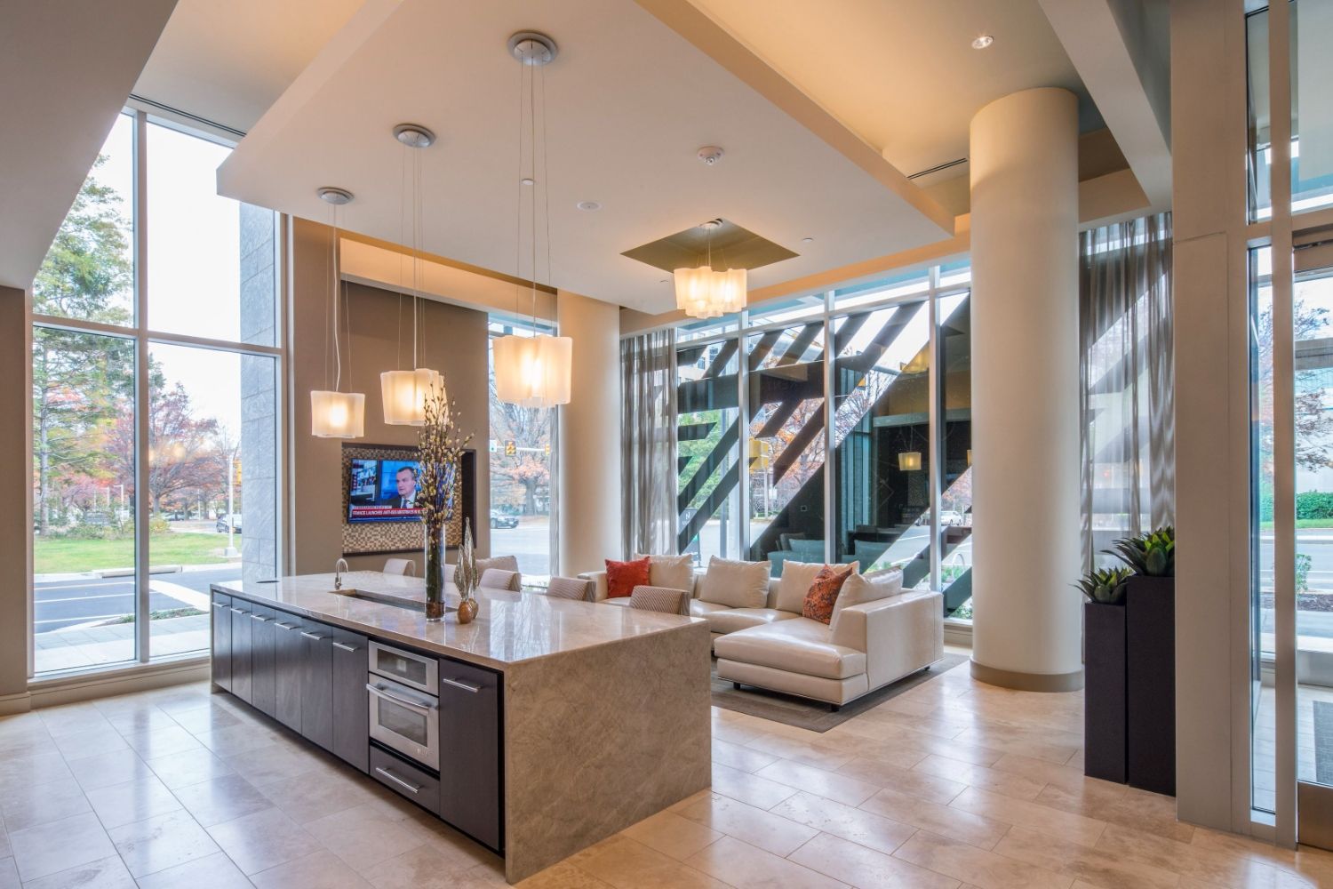 Modern lobby with large windows, a kitchen island, and stylish seating.