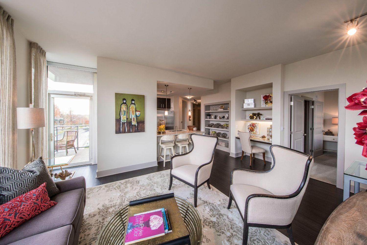 Modern living room with two chairs, a small table, and open kitchen area in a stylish apartment.