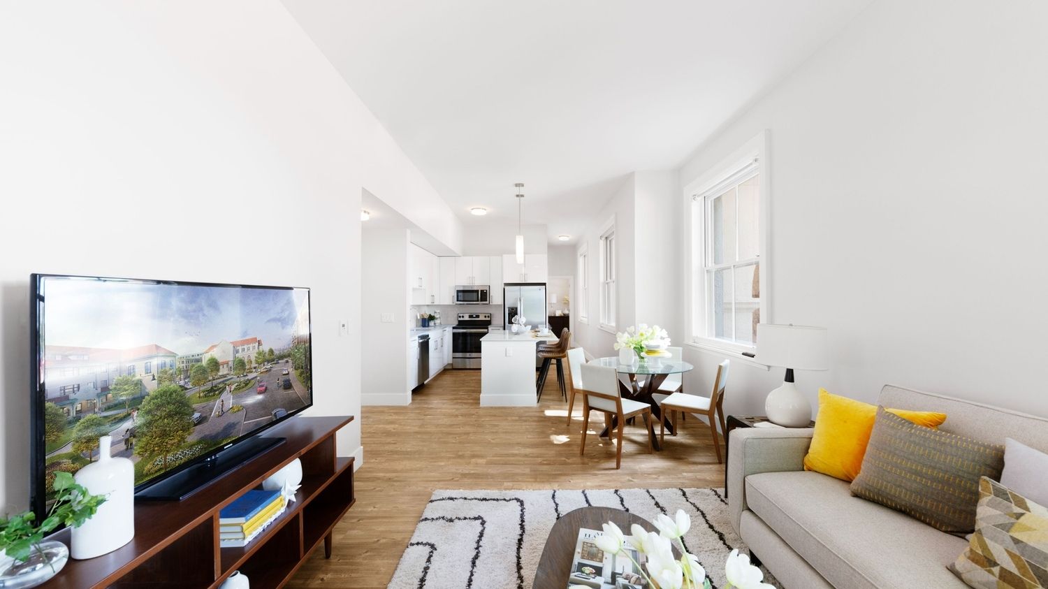 Bright, modern living room and kitchen with minimalist furnishings and light wood flooring.