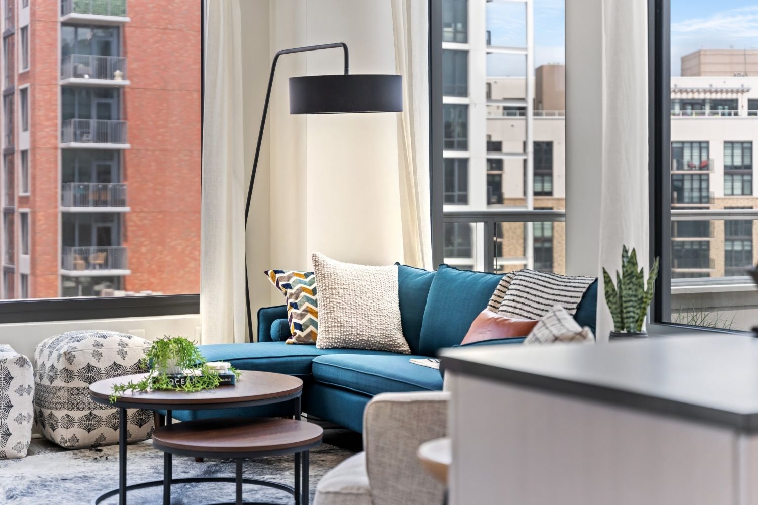 Cozy modern living room with a blue sofa, stylish decor, and large windows.
