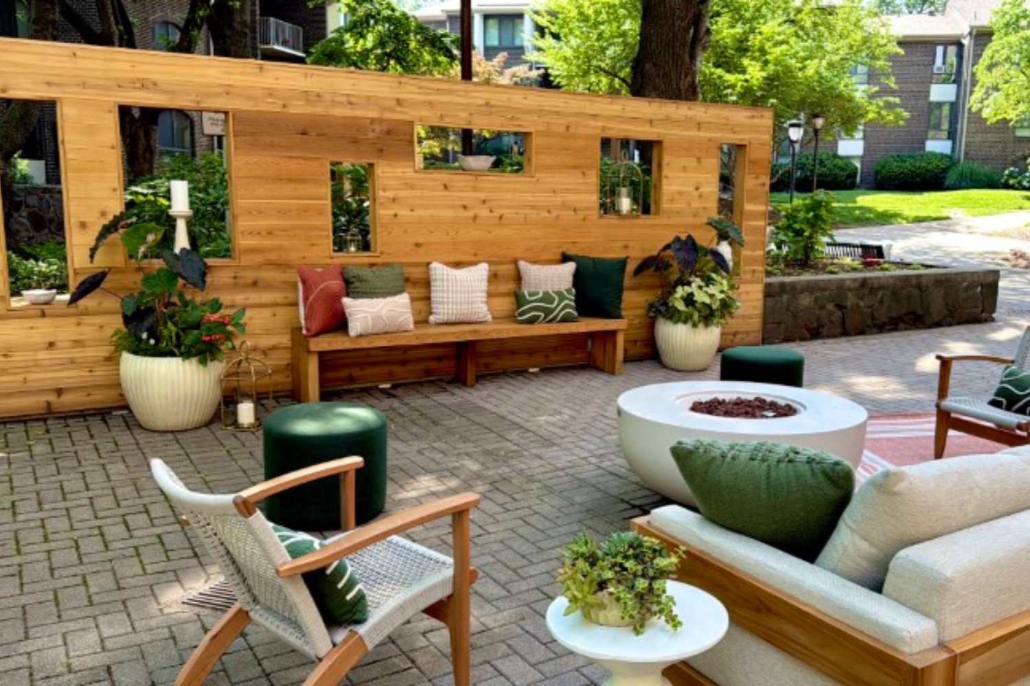 Chic outdoor seating area with wooden wall, plants, and cozy furniture.