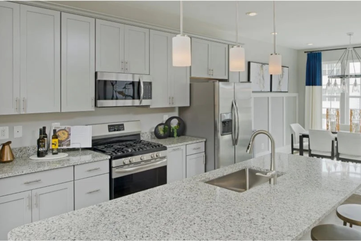 Modern kitchen with white cabinets, stainless steel appliances, and a granite countertop island.