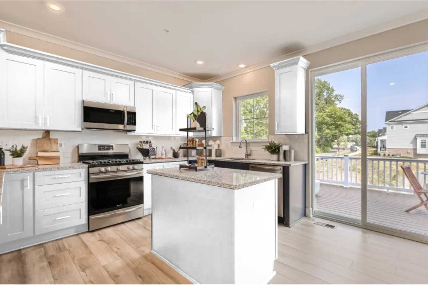 Modern kitchen with white cabinetry, stainless steel appliances, and a sliding glass door.