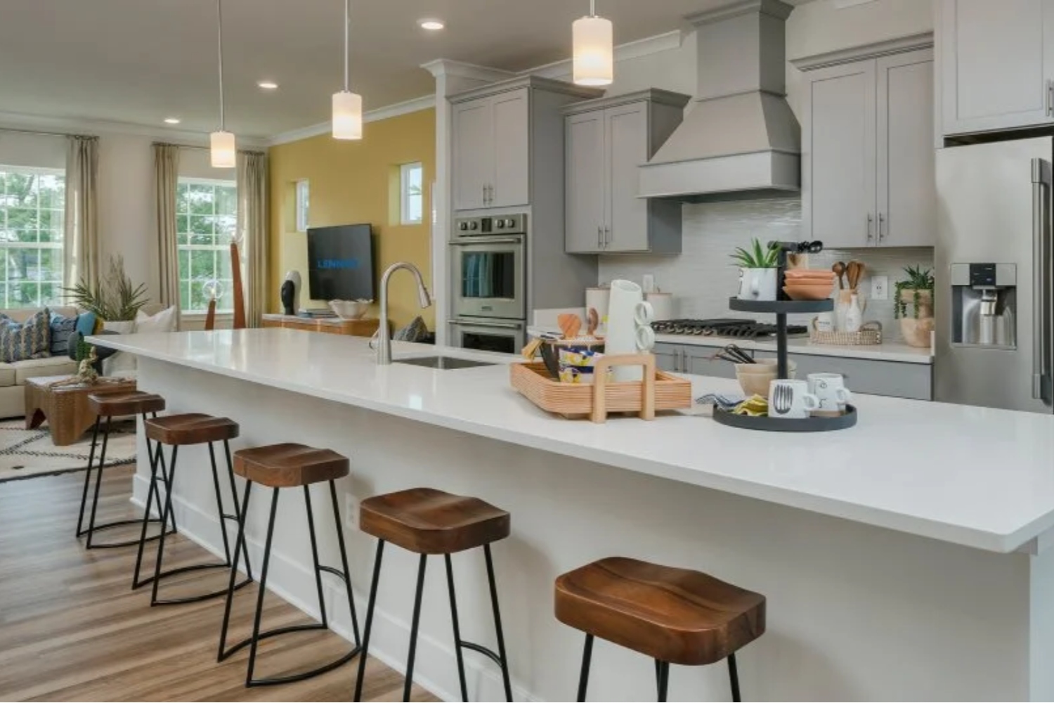 Modern kitchen with gray cabinets, white island, and wooden bar stools.