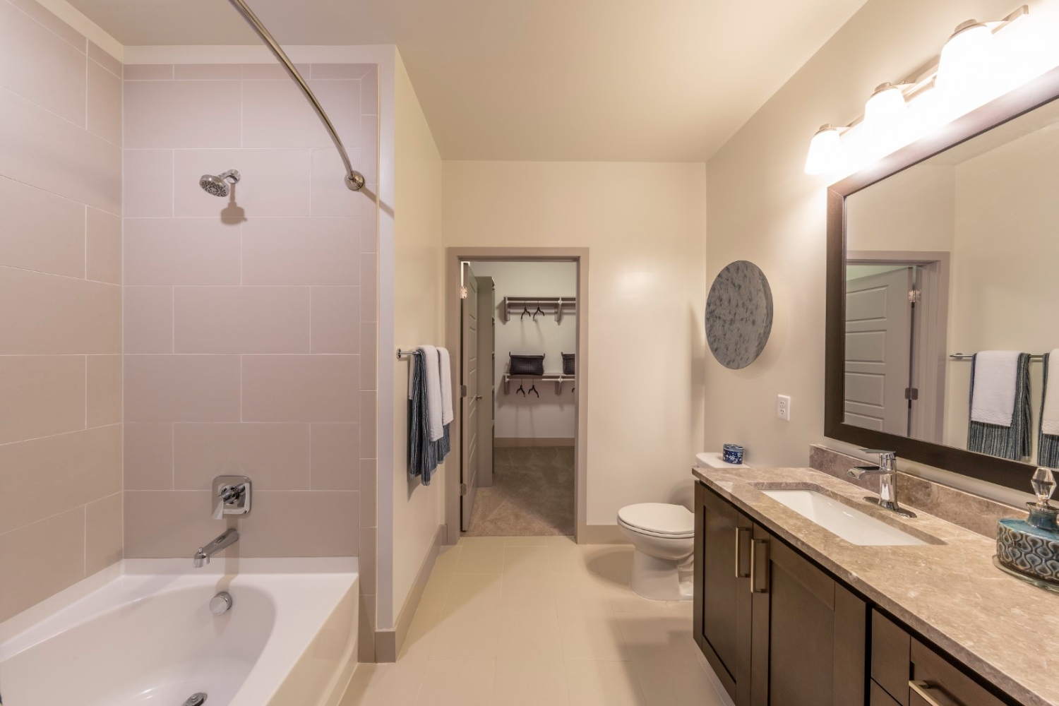 Modern bathroom with a tub, double sink, and an adjoining door to another room.