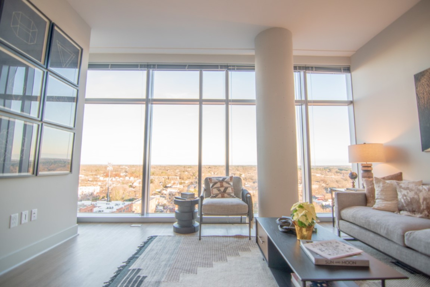 Modern living room with large windows, minimal furniture, and a view of the city.