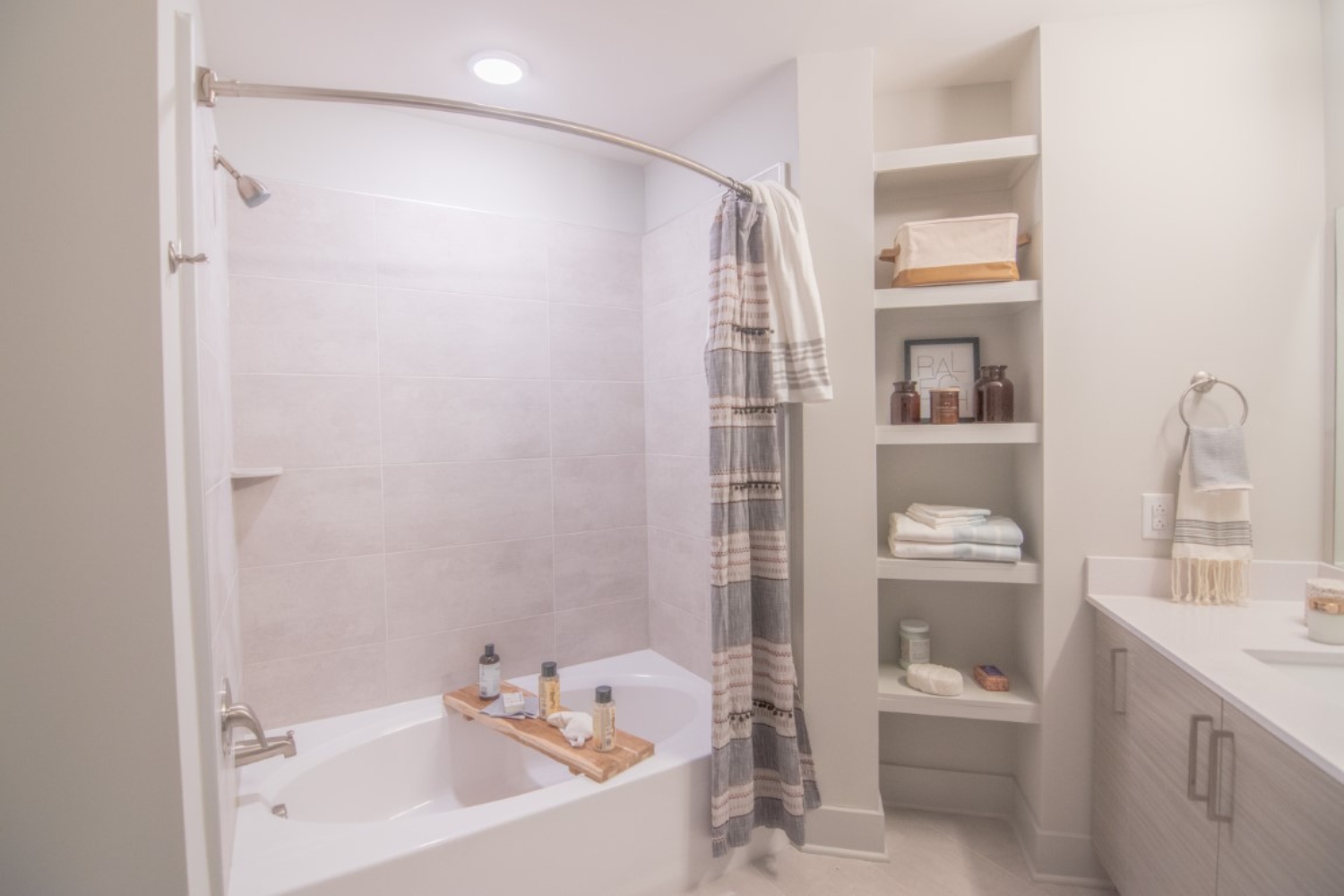 Modern bathroom with a tub, shower, and neatly arranged shelves.