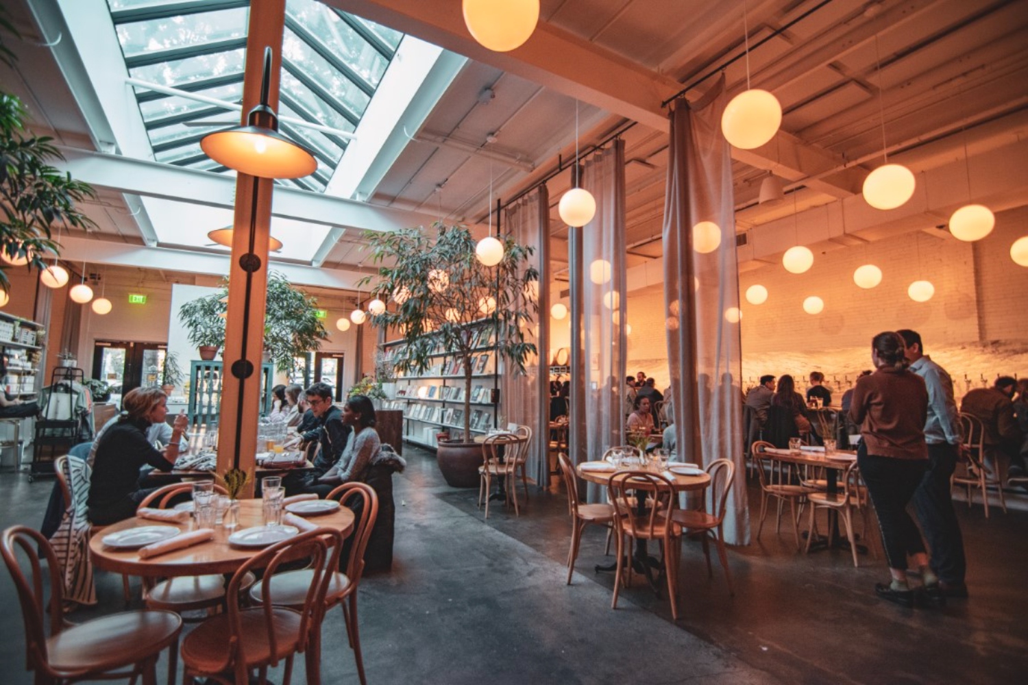 Modern restaurant interior with soft lighting, wooden furniture, and diners enjoying a meal.