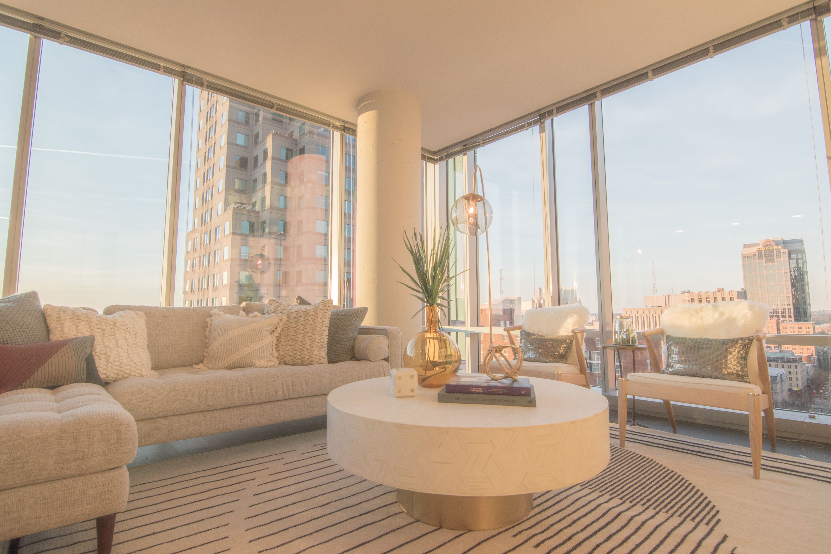Modern living room with large windows, a round coffee table, and cozy seating.