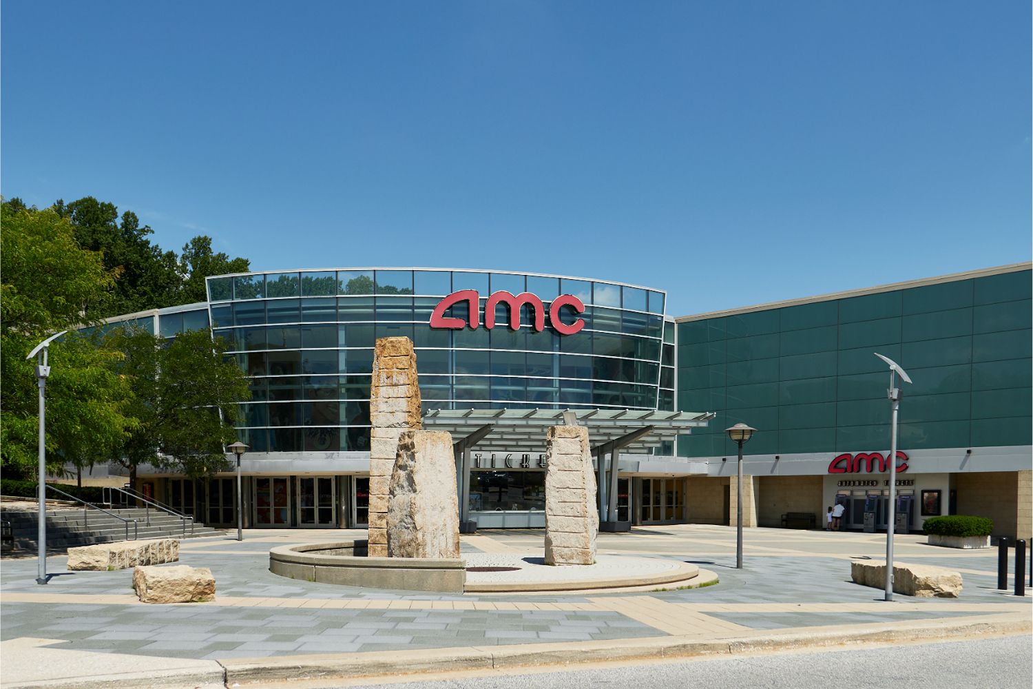 Exterior of AMC Columbia 14 with red AMC signage, stone columns, and a paved plaza.