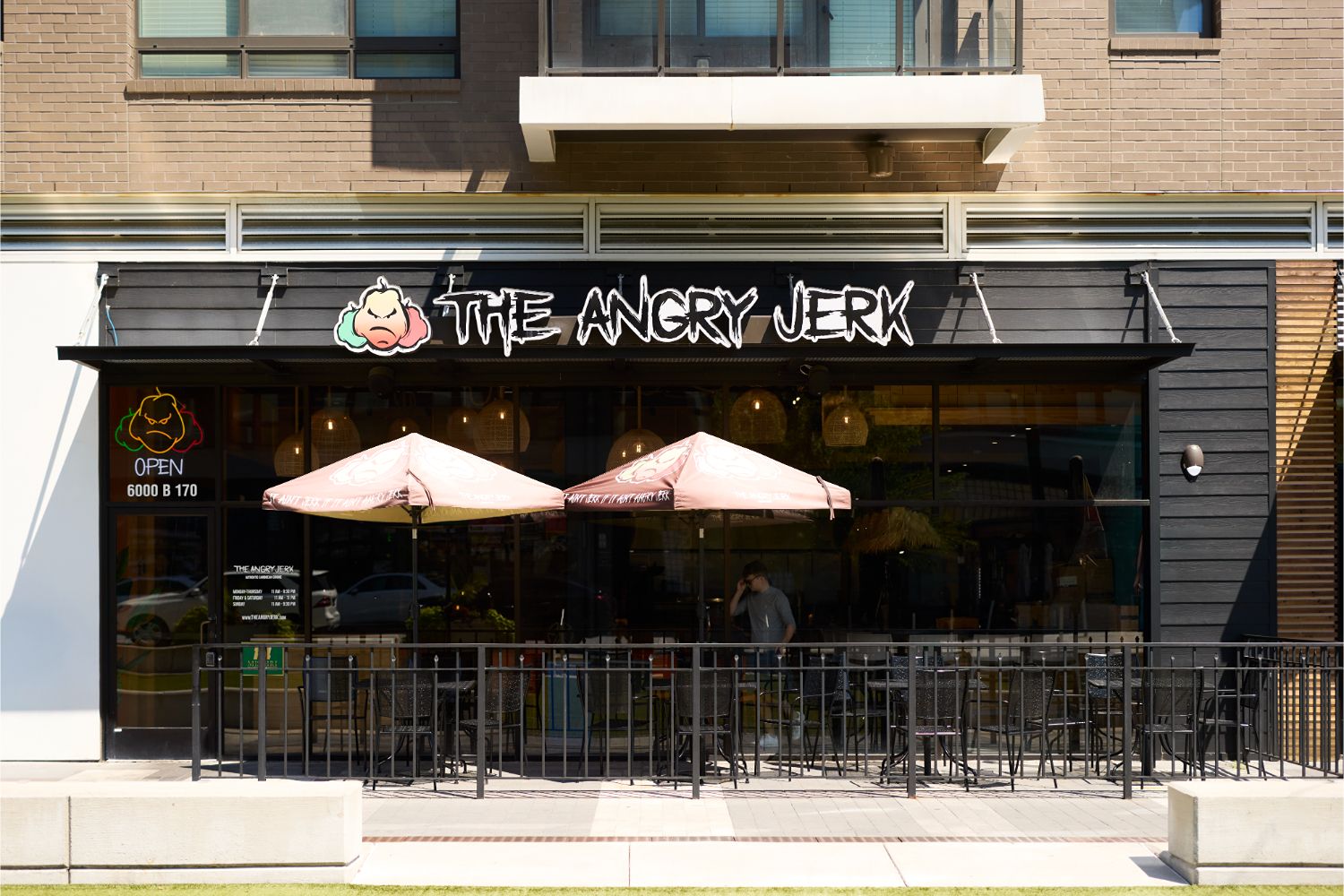 The Angry Jerk restaurant storefront with black signage, patio umbrellas, and outdoor seating.