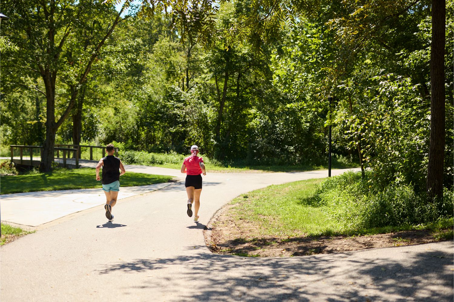 Two people jogging on a paved, tree-lined trail at Bailey Park.