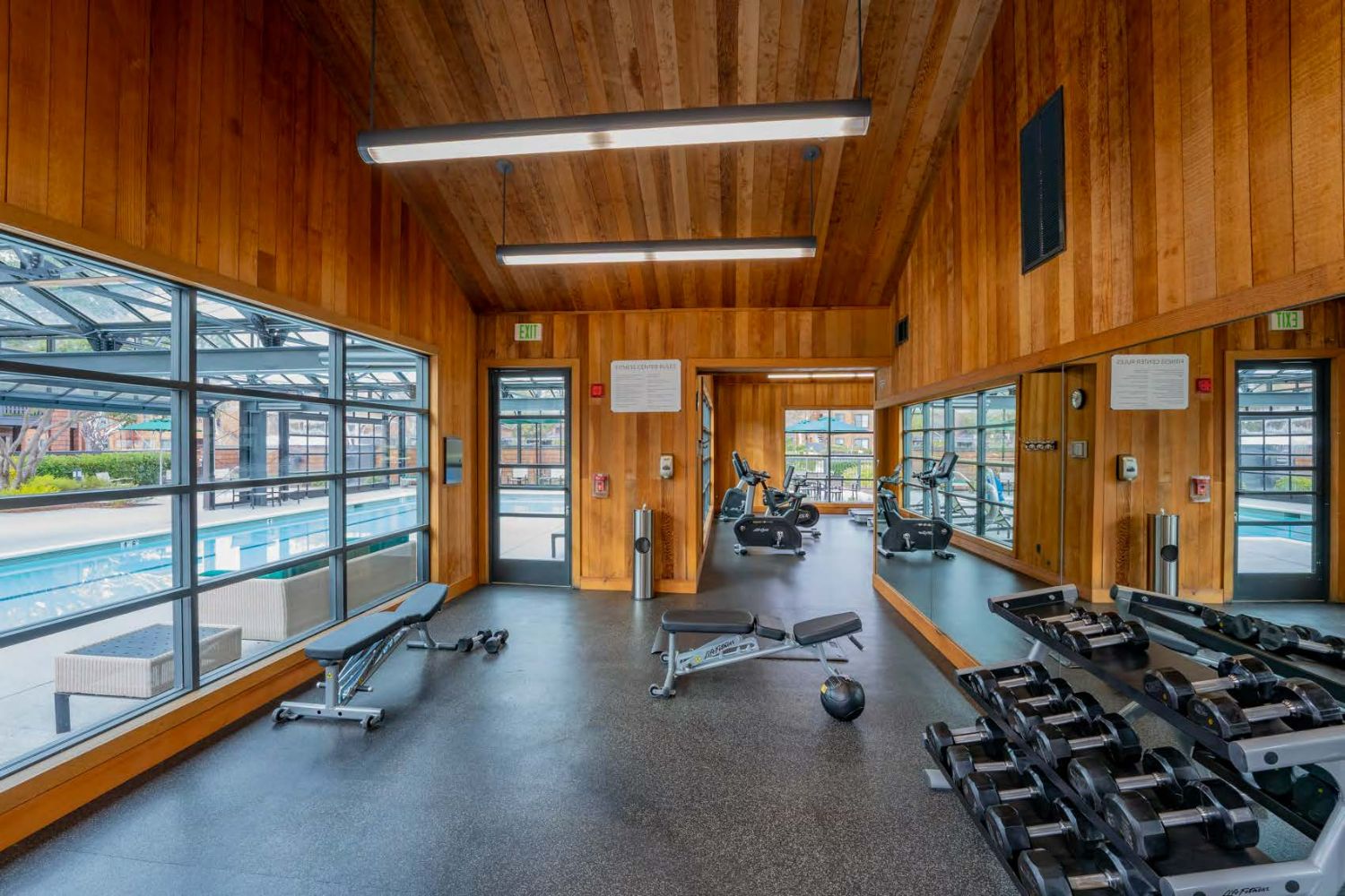 Apartment fitness center with modern gym equipment and large windows