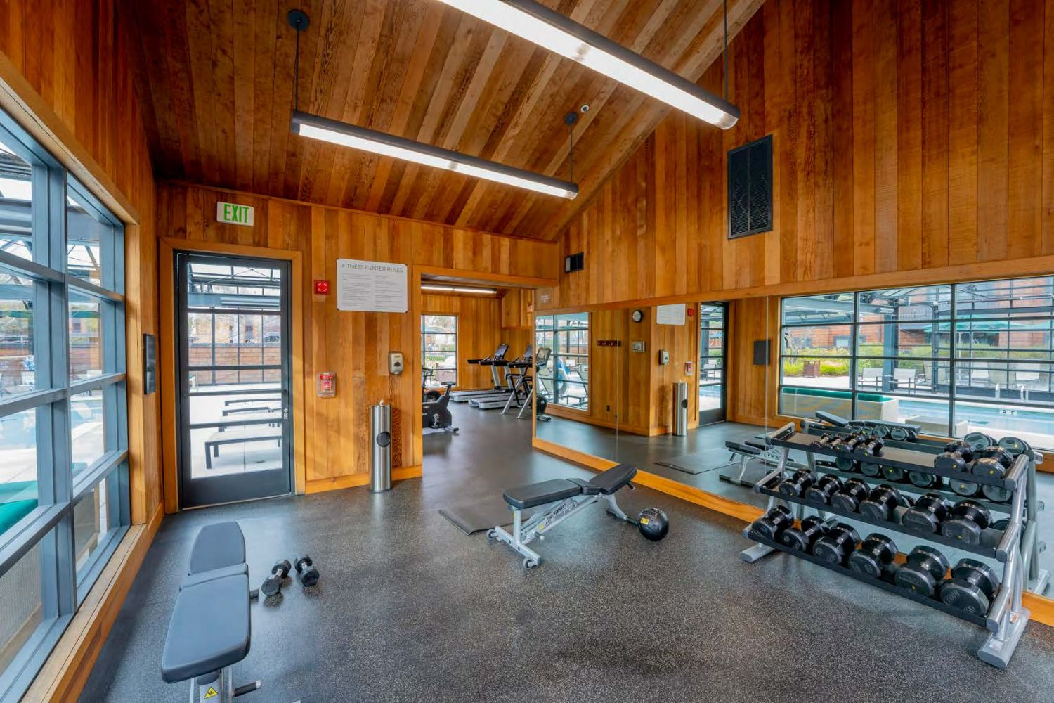 Apartment fitness center with modern gym equipment and large windows