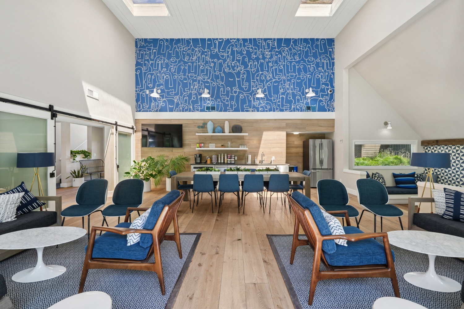 Clubhouse interior with dining table, lounge seating, and large windows with outdoor views