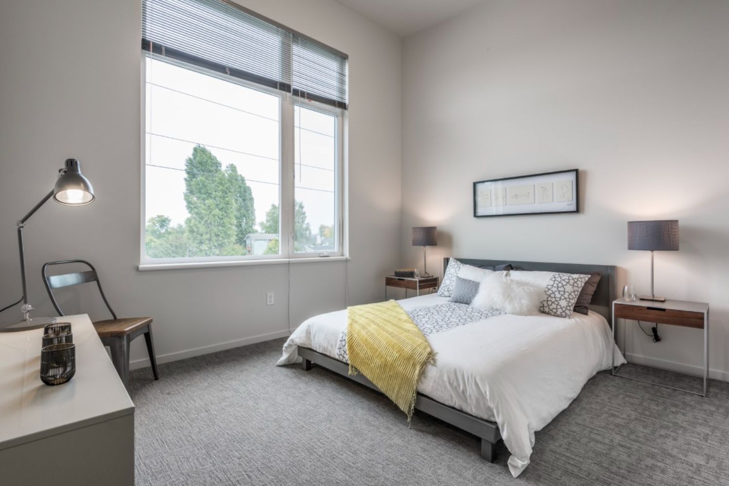 A modern bedroom with a bed, side tables, and large windows.