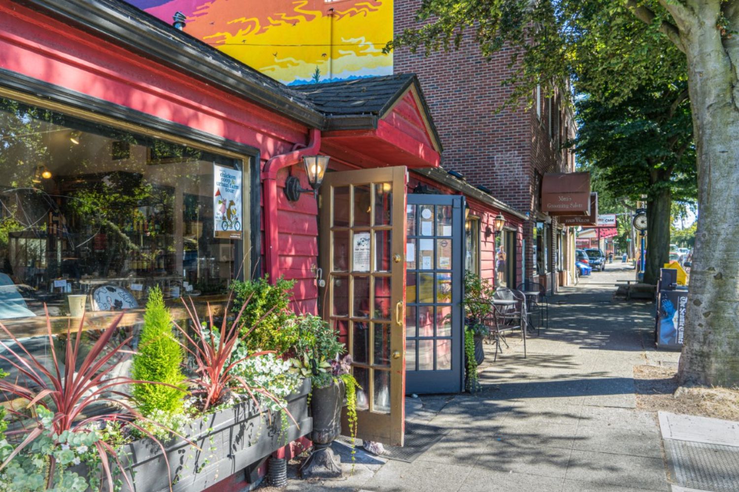 Colorful storefront with plants on a sunny street.