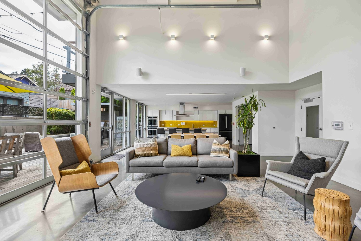 Spacious resident lounge at Janus Apartments featuring seating area, kitchen and dining space, and large windows.