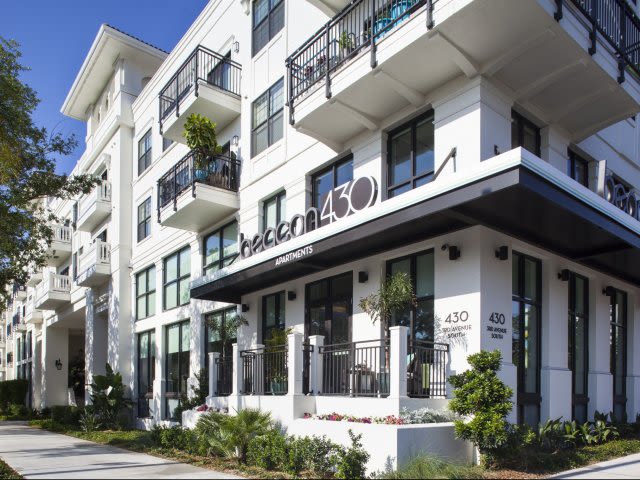 Modern white apartment building with balconies and landscaping.