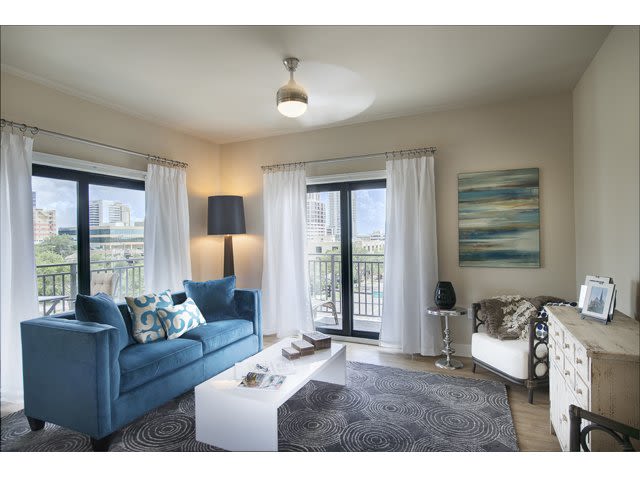 Modern living room with blue sofa, white coffee table, and large windows.