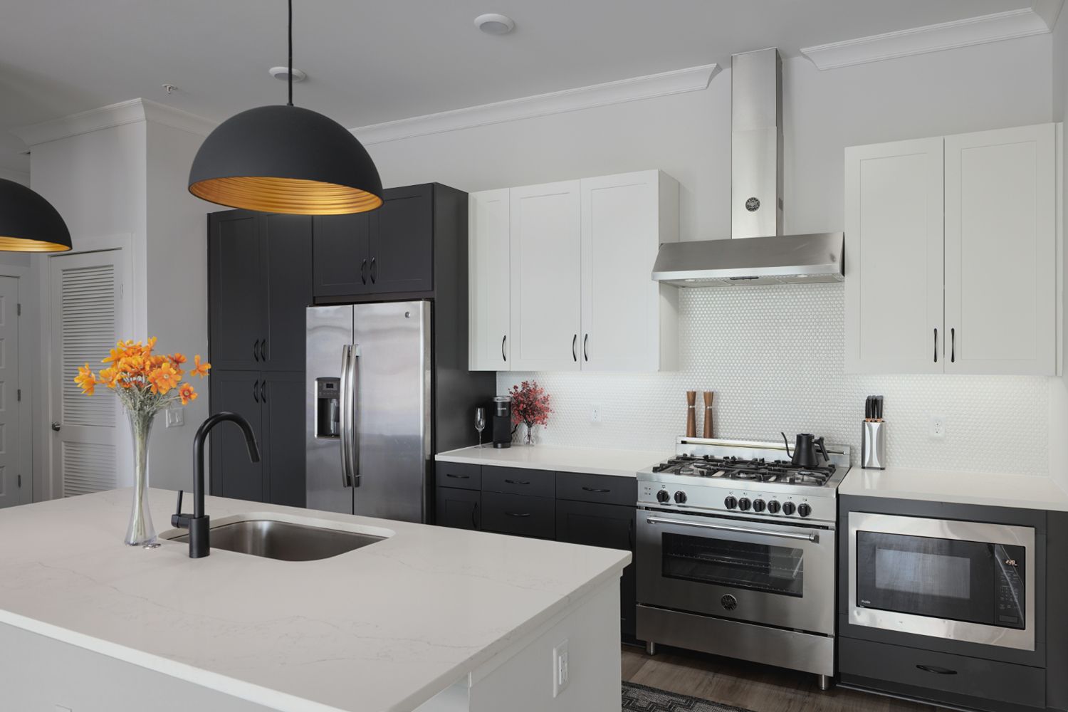 Apartment kitchen with white and dark cabinets, stainless steel appliances, and a sink island.