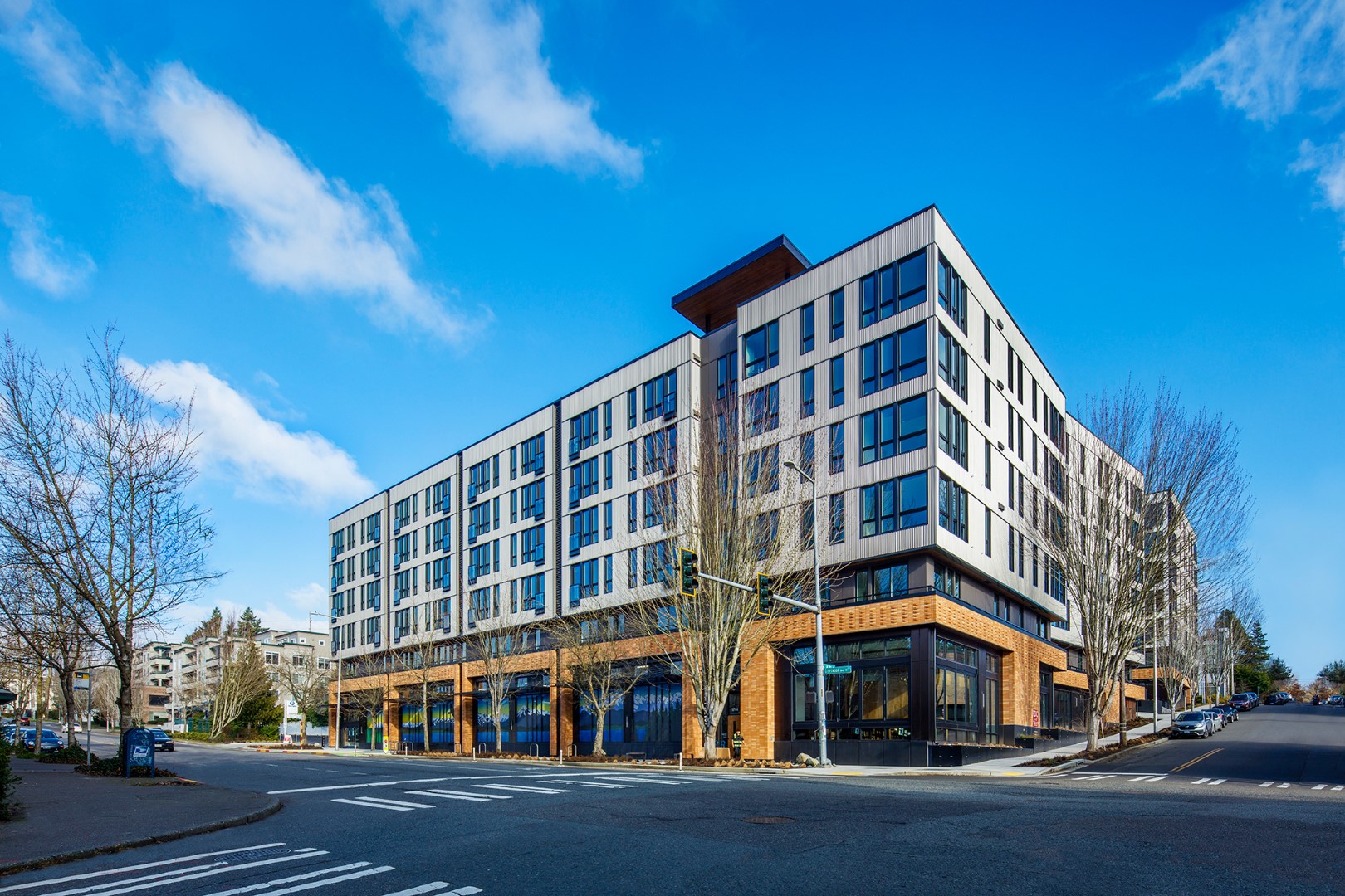 Modern four-story building at a street corner with clear blue sky.