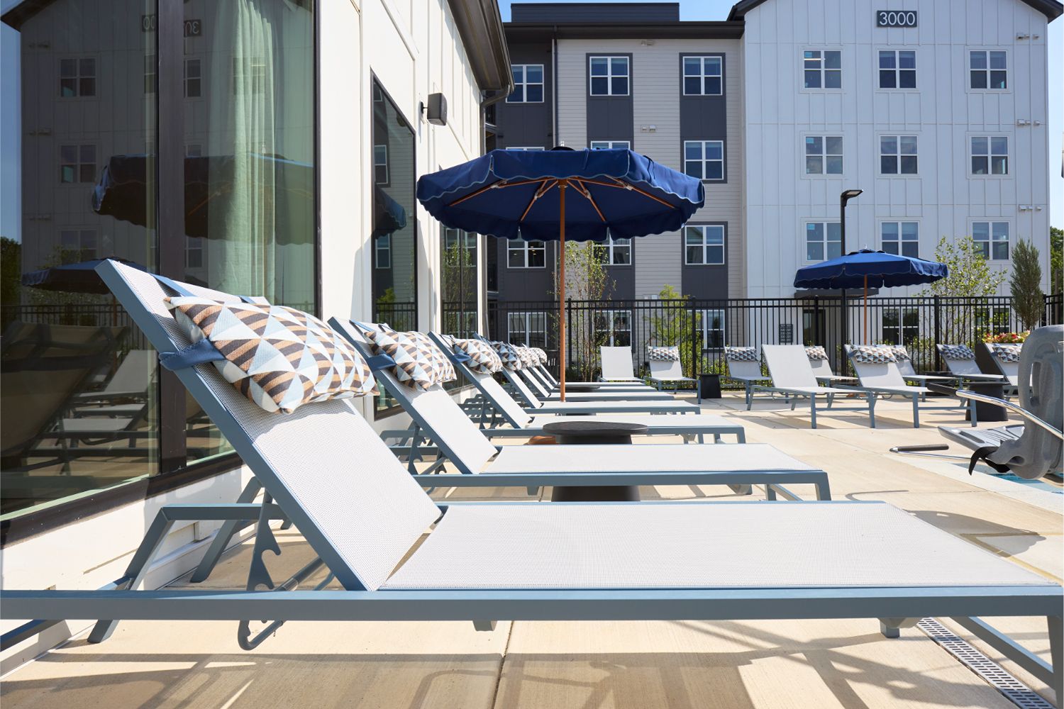 Poolside lounge seating and umbrellas at Alexan Brandywine luxury apartments in Brandywine, MD.