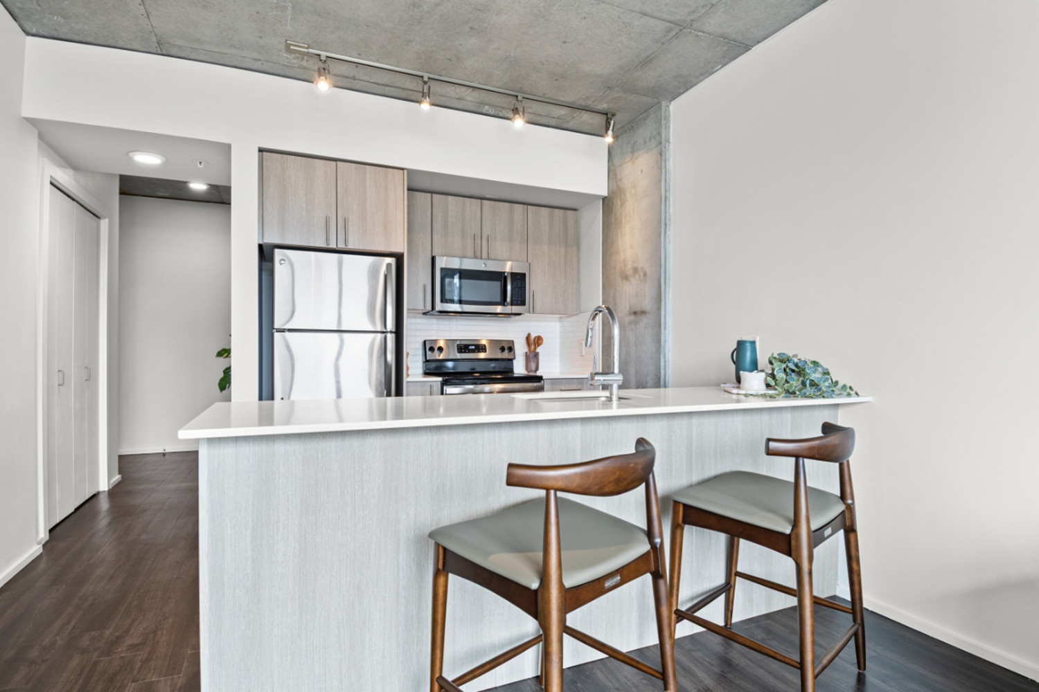 Modern apartment kitchen at NV Apartments with quartz countertops, stainless steel appliances, and island seating.